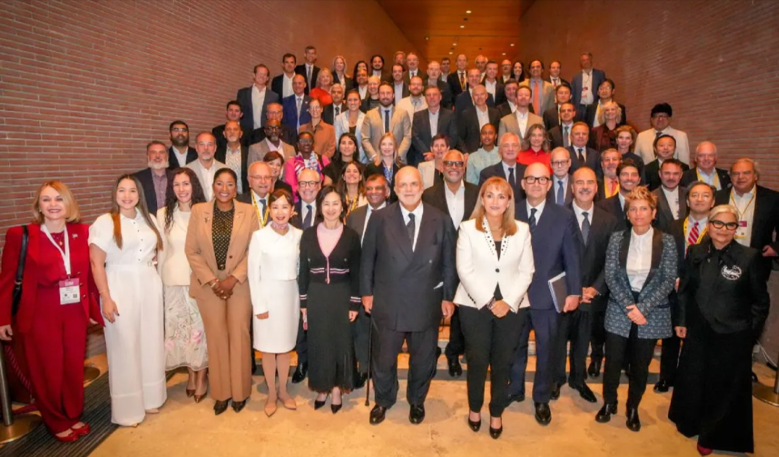 A room full of WTTC members posing for the camera, standing on a upward going floor.